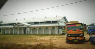 Selain semak dan rumput liar, tampak pula angkutan CPO parkir di sisi pasar