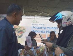 BRI terus mendorong inklusi keuangan dan peningkatkan literasi serta transaksi digital, terutama di sentra-sentra perdagangan dengan menyediakan sarana pembayaran berupa QRIS BRI dan BRIMO. Foto SBM Niki Satria Lubis saat mengarahkan warga pembayaran digital