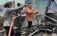 Bu Bhabin Bhabinkamtibmas Polsek Bangko mengangkat selang saat membantu pemadaman kebakaran di Kota Bangko