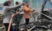 Bu Bhabin Bhabinkamtibmas Polsek Bangko mengangkat selang saat membantu pemadaman kebakaran di Kota Bangko